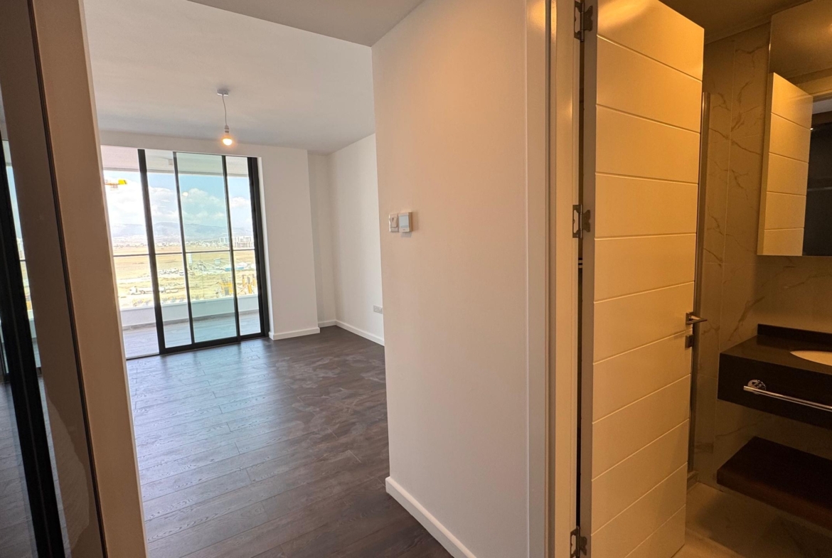 kıbrıs Koyu ahşap zeminler, sağda lavabolu şık bir banyo ve muhteşem şehir ve dağ manzaralı bir balkona açılan aydınlık bir yaşam alanı içeren modern daire, İskele Long Beach satılık daire seçenekleri arayanlar için mükemmeldir. aysan_giti