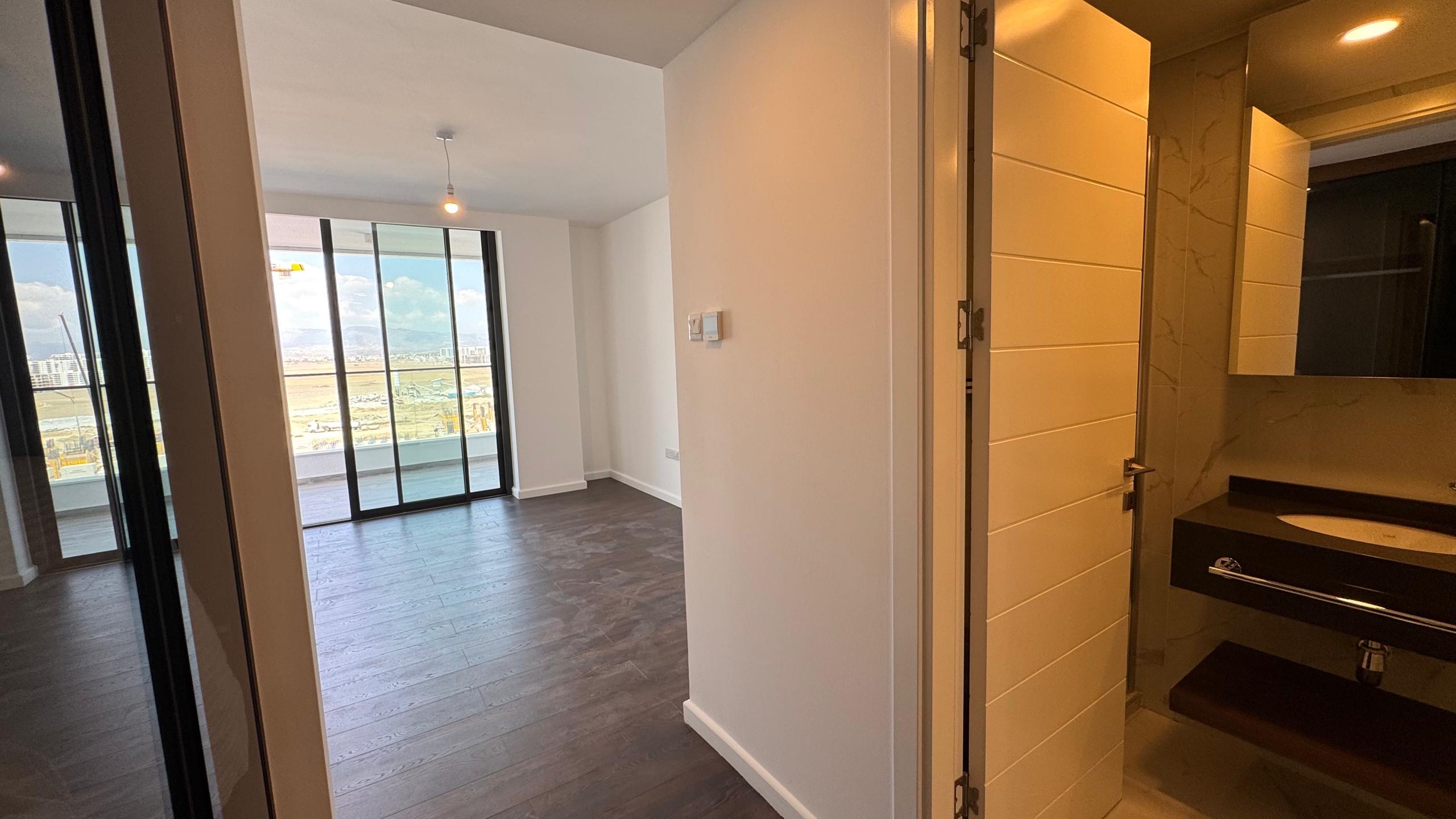 kıbrıs Koyu ahşap zeminler, sağda lavabolu şık bir banyo ve muhteşem şehir ve dağ manzaralı bir balkona açılan aydınlık bir yaşam alanı içeren modern daire, İskele Long Beach satılık daire seçenekleri arayanlar için mükemmeldir. aysan_giti