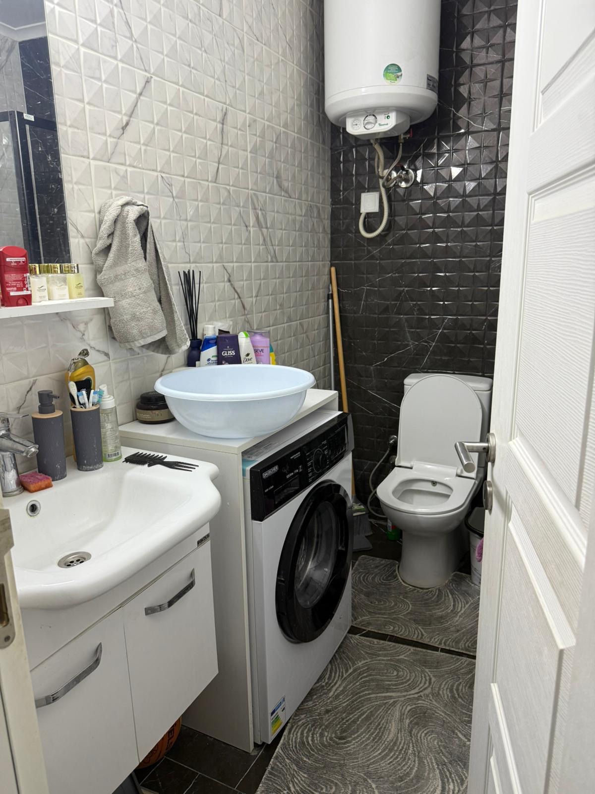 kıbrıs Lavabo, çamaşır makinesi, tuvalet ve su ısıtıcısının bulunduğu küçük bir banyo. Tuvalet malzemeleri ve temizlik malzemeleri raflarda, büyük bir lavabo ise çamaşır makinesinin üzerinde yer alıyor. Duvarlarda gri tonlarda dokulu karolar var. aysan_giti