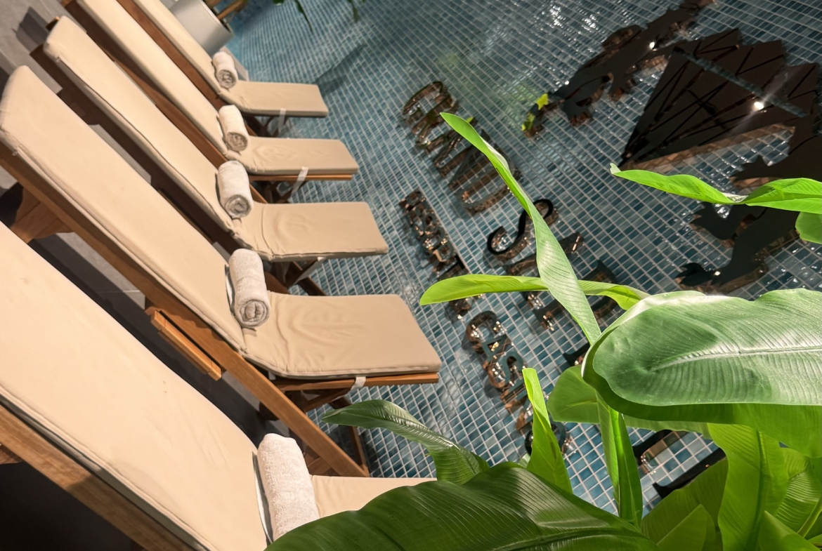 kıbrıs Kapalı havuzun yanındaki kiremitli duvarda yer alan bej renkli şezlonglar, İskele Long Beach kiralık daire arayanlar ya da İskele Long Beach satılık daire ile ilgilenenler için modern ve rahatlatıcı bir spa ortamı yaratıyor. aysan_giti