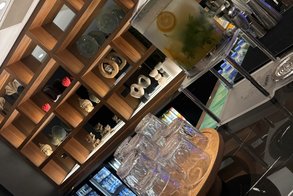 kıbrıs Ahşap tepsiler üzerinde üst üste dizilmiş içki bardaklarıyla çevrili, limon ve nane suyu dolu bir cam sebilden oluşan bir içecek istasyonu - İskele Long Beach kiralık daire ilanlarına göz atarken veya Kuzey Kıbrıs gayrimenkulünü tartışırken mükemmel bir ferahlık. aysan_giti