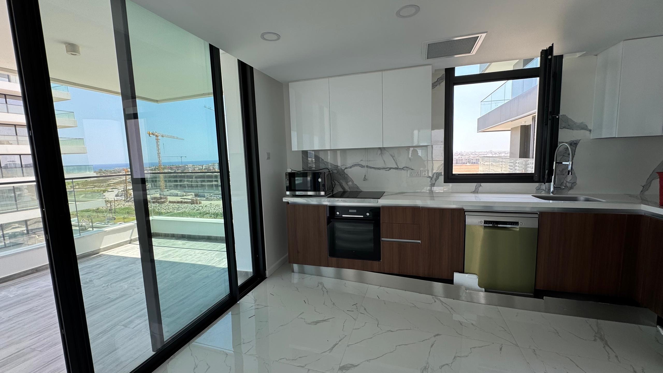 kıbrıs Parlak beyaz ve ahşap dolaplar, ankastre fırın, mikrodalga fırın ve bulaşık makinesi içeren modern mutfak. Grand Sapphire Resort & Residence; 7 yıldızlı otel konseptinde yaşam Kıbrıs'ın balkonundan şehir manzarasının ve bir inşaat vincinin keyfini çıkarın. Mermer tarzı karo zemin. aysan_giti