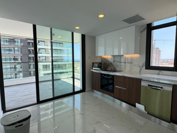 kıbrıs Beyaz ve ahşap dolaplar, ankastre cihazlar ve büyük pencereli modern mutfak. Cam kapılar, şık bir Kuzey Kıbrıs satılık daire arayanlar için ideal olan şehir manzaralı geniş bir balkona açılmaktadır. Mermer desenli zeminler aydınlık ve havadar mekânı zenginleştirmektedir. aysan_giti